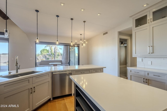 kitchen featuring sink, stainless steel dishwasher, a kitchen island, light wood-type flooring, and decorative light fixtures