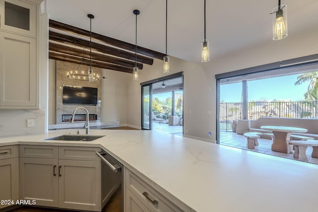 kitchen with hanging light fixtures, sink, light stone counters, and beam ceiling