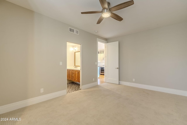 unfurnished bedroom featuring ensuite bath, ceiling fan, light colored carpet, and sink