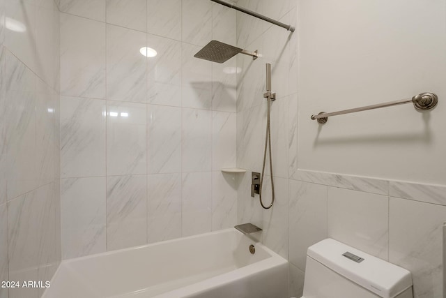 bathroom featuring tile walls, tiled shower / bath, and toilet