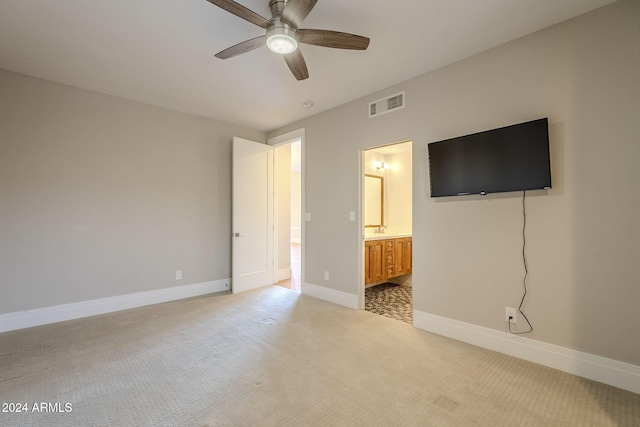 unfurnished bedroom featuring light carpet, ceiling fan, and ensuite bath