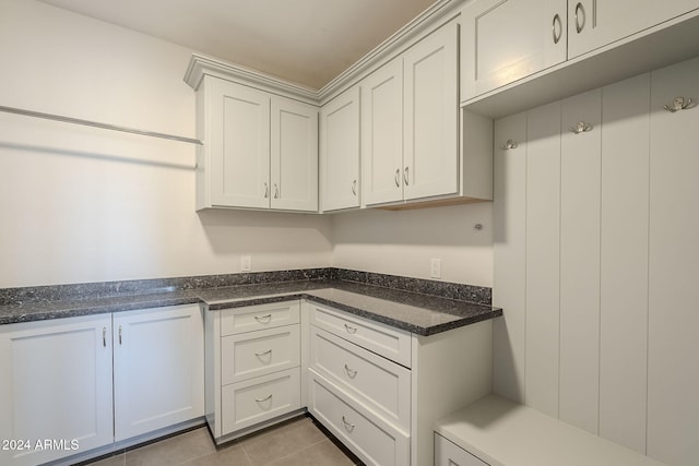 kitchen with dark stone countertops, white cabinetry, and light tile patterned floors