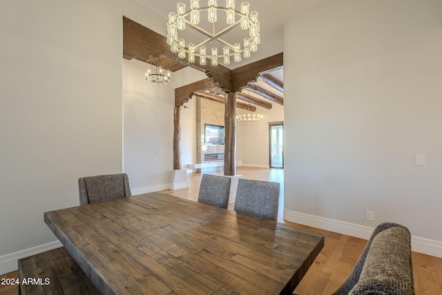 unfurnished dining area with an inviting chandelier, hardwood / wood-style floors, and beam ceiling