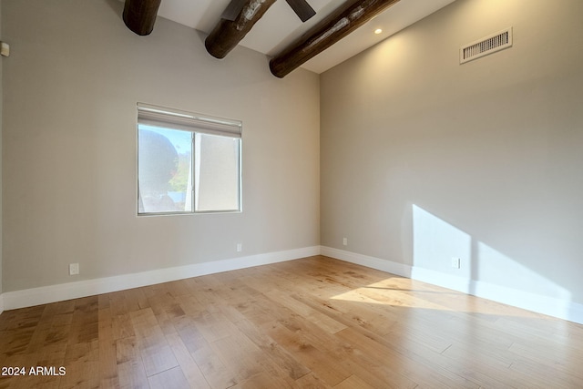 empty room with beamed ceiling, ceiling fan, and light hardwood / wood-style flooring