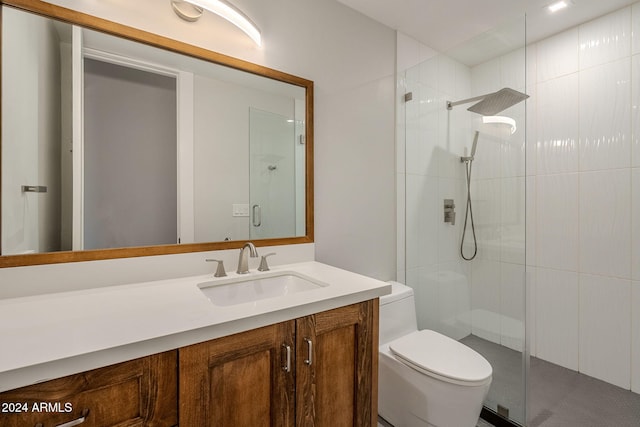 bathroom featuring toilet, vanity, and a shower with shower door