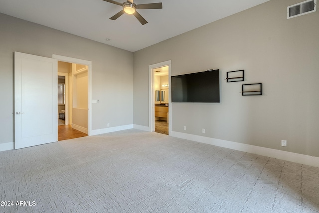 unfurnished bedroom with ensuite bathroom, ceiling fan, and light carpet