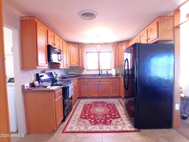 kitchen featuring light tile patterned floors, sink, and black appliances