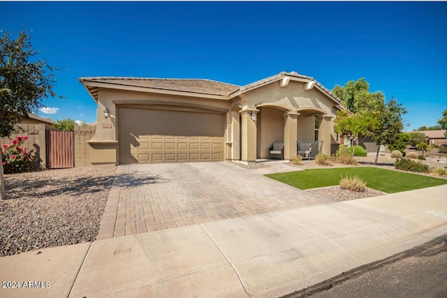 view of front of home with a tile roof, stucco siding, decorative driveway, an attached garage, and a gate