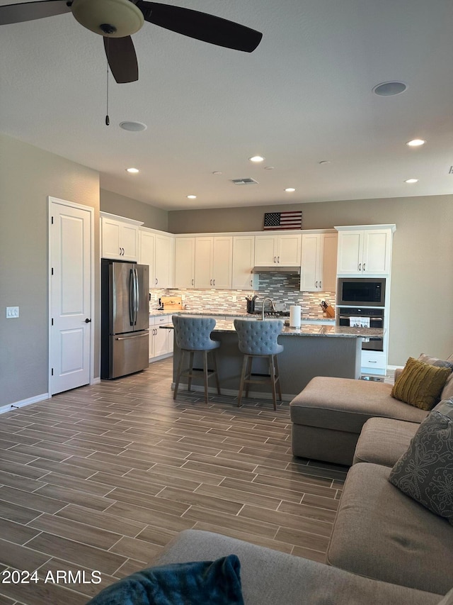 living room with dark wood-type flooring, ceiling fan, and sink