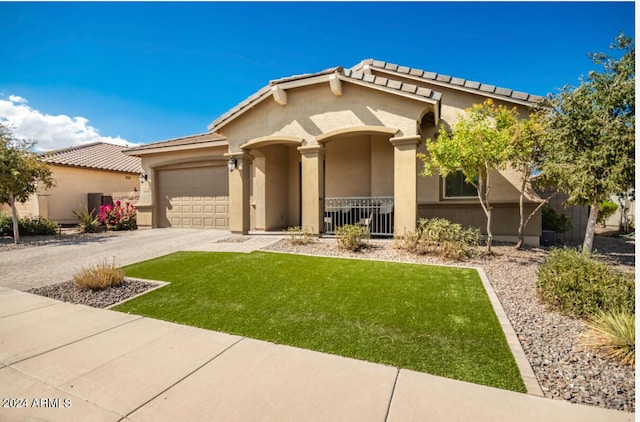 mediterranean / spanish-style house with driveway, stucco siding, a front lawn, a garage, and a tiled roof