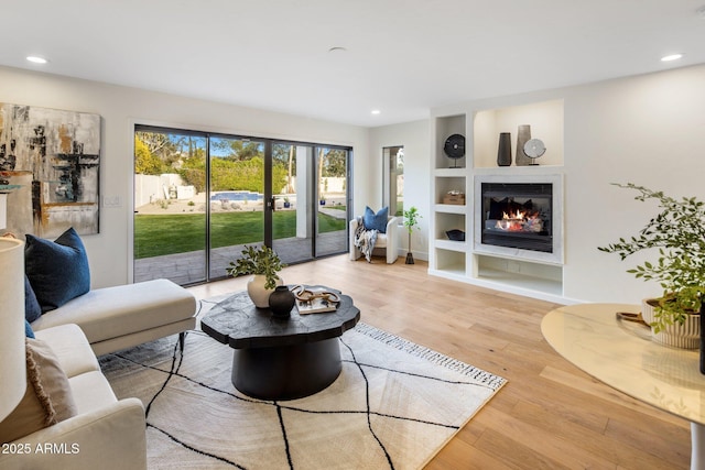 living room featuring built in shelves and light wood-type flooring