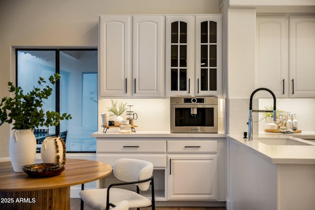 bar featuring white cabinetry, oven, sink, and decorative backsplash