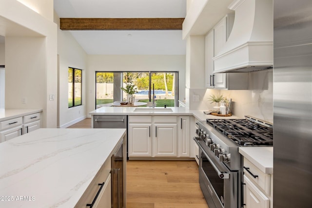 kitchen featuring sink, custom range hood, stainless steel appliances, light hardwood / wood-style floors, and white cabinets