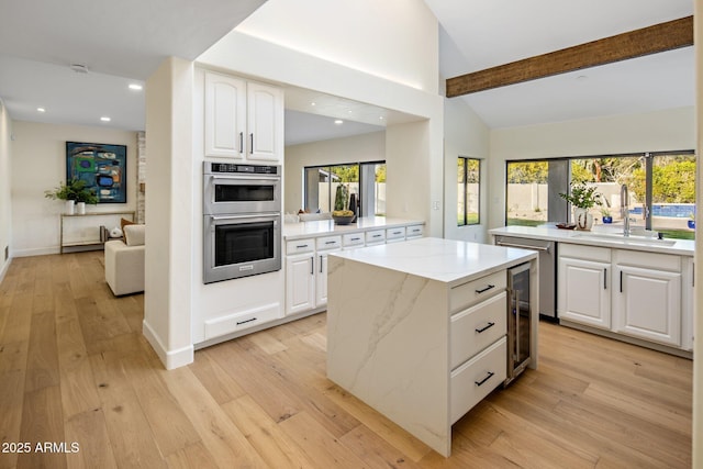 kitchen with stainless steel double oven, sink, light hardwood / wood-style flooring, and white cabinets