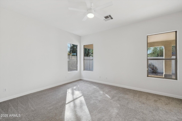 carpeted spare room with plenty of natural light, visible vents, ceiling fan, and baseboards