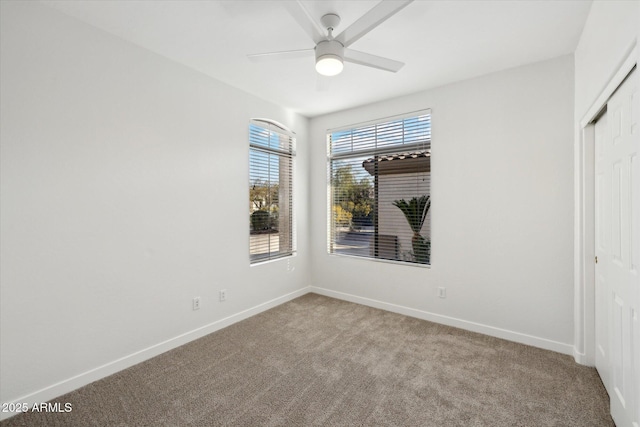 unfurnished room with baseboards, a ceiling fan, and light colored carpet