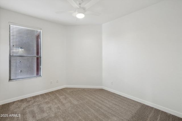 carpeted spare room featuring a ceiling fan and baseboards