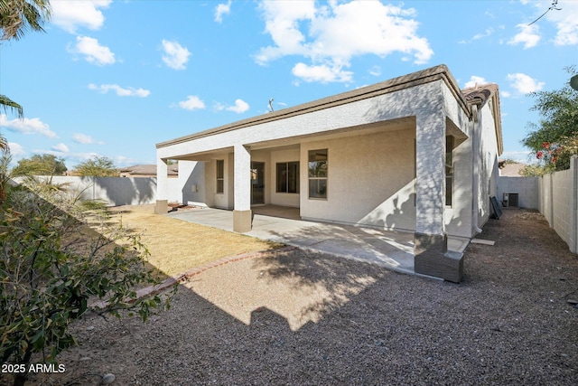 back of property with stucco siding, a fenced backyard, central AC, and a patio