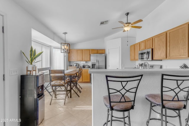 kitchen featuring hanging light fixtures, light tile patterned floors, lofted ceiling, ceiling fan with notable chandelier, and appliances with stainless steel finishes