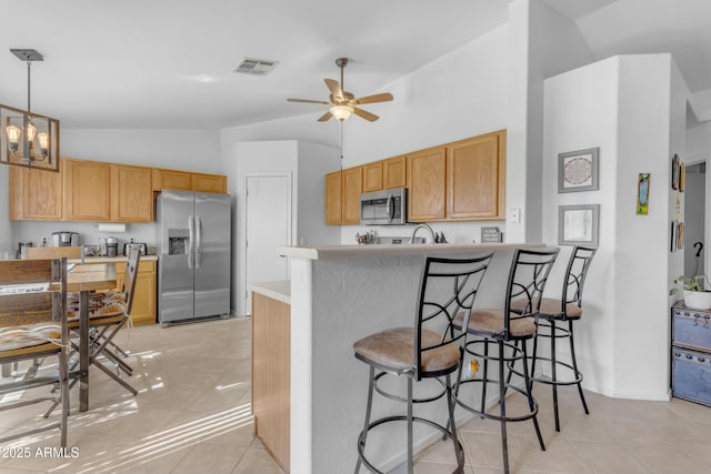 kitchen with kitchen peninsula, hanging light fixtures, light tile patterned floors, ceiling fan with notable chandelier, and appliances with stainless steel finishes