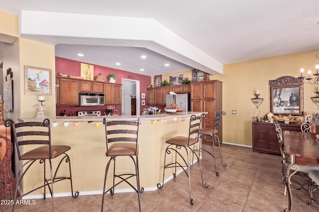5314 W Bowker St, Laveen, AZ 85339 - kitchen with appliances with stainless steel finishes, a breakfast bar area, recessed lighting, light tile patterned floors, and brown cabinetry