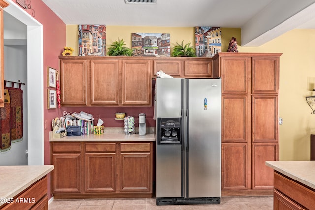5314 W Bowker St, Laveen, AZ 85339 - kitchen with stainless steel fridge with ice dispenser, light countertops, brown cabinetry, and light tile patterned floors