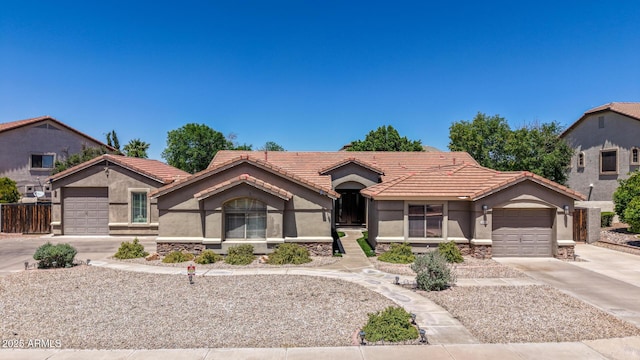 mediterranean / spanish-style house with an attached garage, a tile roof, stone siding, stucco siding, and driveway