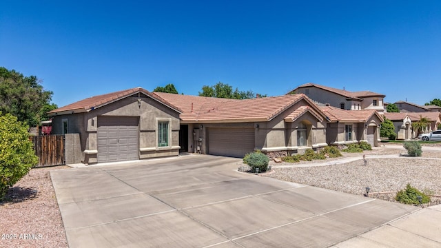 ranch-style home featuring a tile roof, fence, concrete driveway, an attached garage, and stucco siding