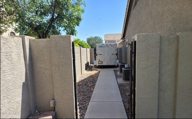 view of side of property with fence, central AC unit, a gate, and stucco siding