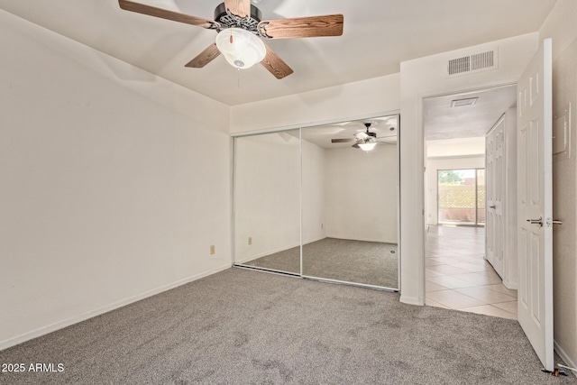 unfurnished bedroom featuring tile patterned floors, carpet, a ceiling fan, visible vents, and a closet