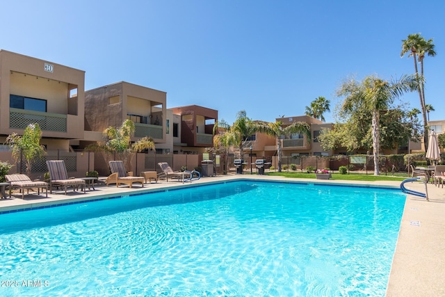 community pool with fence, area for grilling, and a residential view