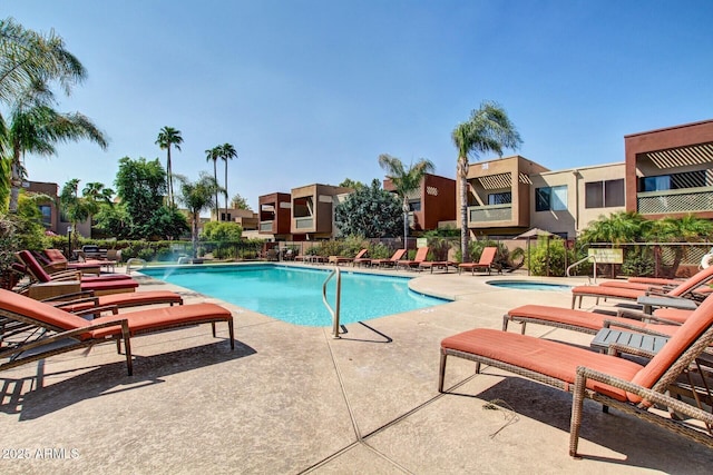 community pool featuring fence, a patio, and a residential view