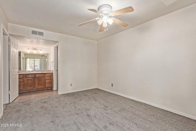 unfurnished bedroom with light carpet, a sink, ensuite bath, baseboards, and visible vents