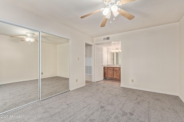 unfurnished bedroom featuring baseboards, carpet flooring, connected bathroom, and ceiling fan with notable chandelier