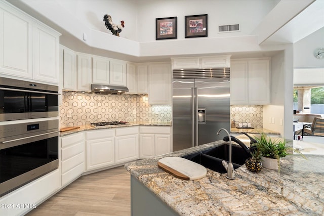 kitchen featuring white cabinetry, sink, stainless steel appliances, and light stone counters