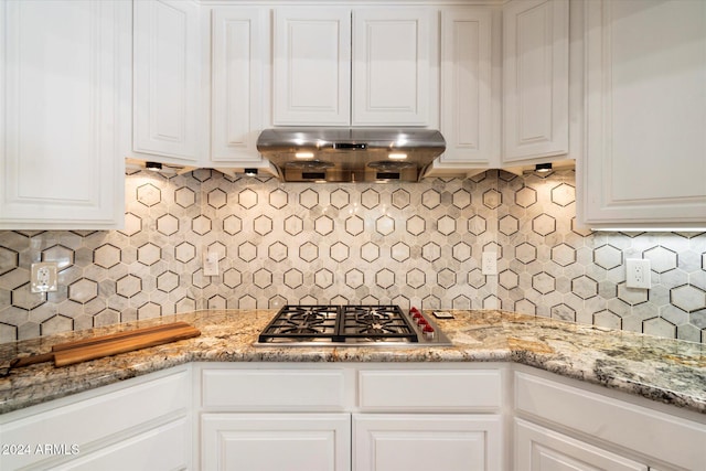 kitchen featuring tasteful backsplash, light stone counters, exhaust hood, white cabinetry, and stainless steel gas stovetop