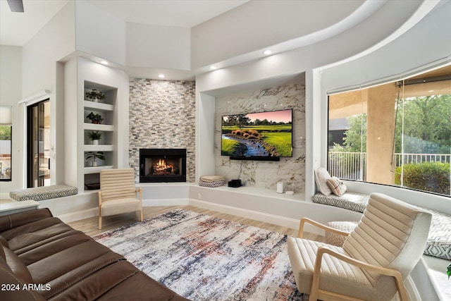 living room with a fireplace, built in shelves, hardwood / wood-style floors, and a high ceiling