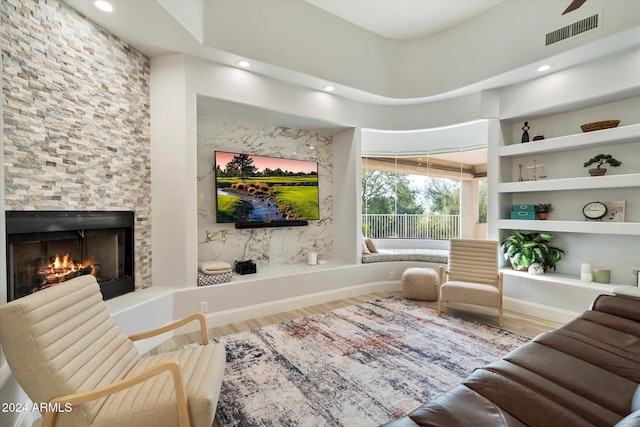 interior space with hardwood / wood-style flooring, built in shelves, a fireplace, and a high ceiling