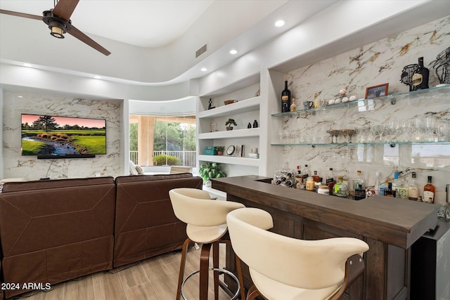 bar featuring built in shelves, ceiling fan, and light wood-type flooring