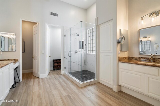 bathroom featuring a high ceiling, vanity, hardwood / wood-style flooring, and a shower with shower door