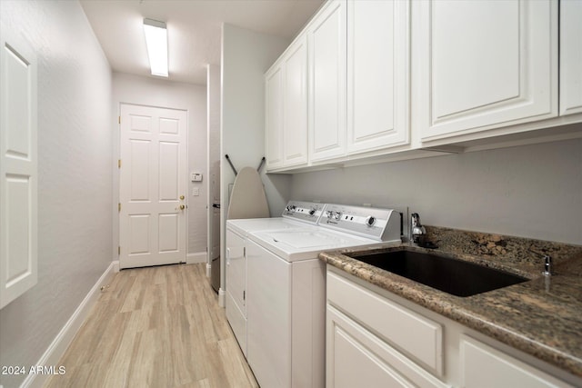 laundry room with cabinets, sink, washer and dryer, and light wood-type flooring