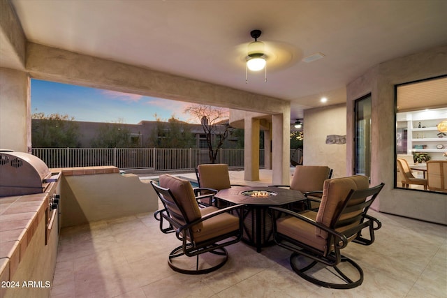 patio terrace at dusk with a fire pit, ceiling fan, and area for grilling