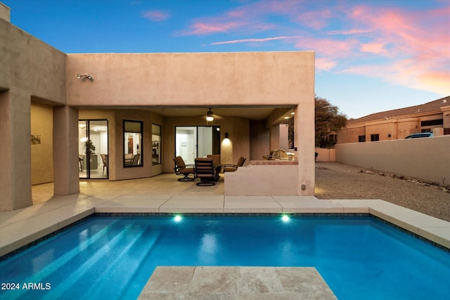 pool at dusk featuring a patio area and ceiling fan