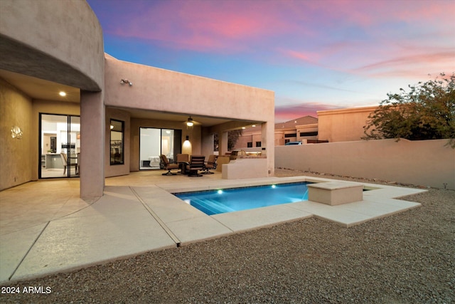 pool at dusk with area for grilling and a patio area