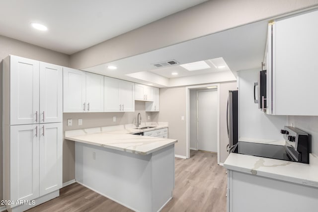 kitchen with white cabinetry, stainless steel appliances, light hardwood / wood-style floors, and sink