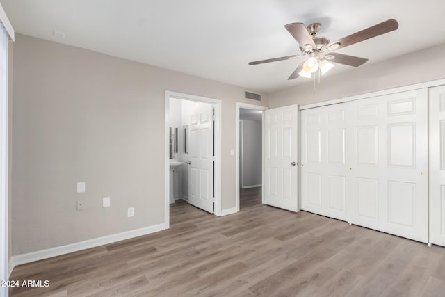 unfurnished bedroom featuring light wood-type flooring, connected bathroom, ceiling fan, and a closet