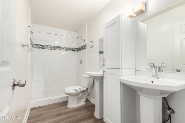 bathroom with hardwood / wood-style floors, tiled shower, and toilet