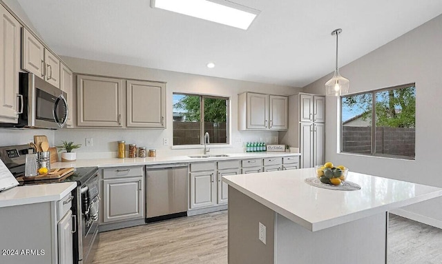 kitchen featuring stainless steel appliances, light hardwood / wood-style floors, vaulted ceiling, and plenty of natural light