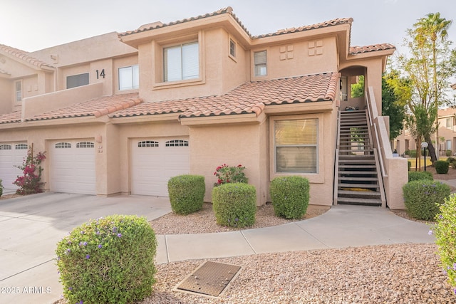 view of front of house featuring driveway, an attached garage, stairway, and stucco siding