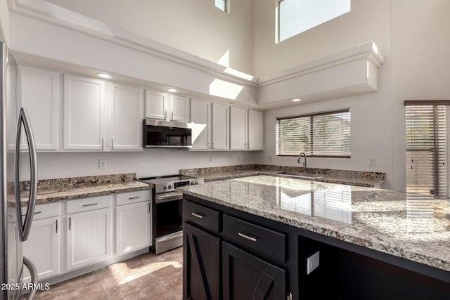 kitchen with plenty of natural light, white cabinetry, stainless steel appliances, and a sink